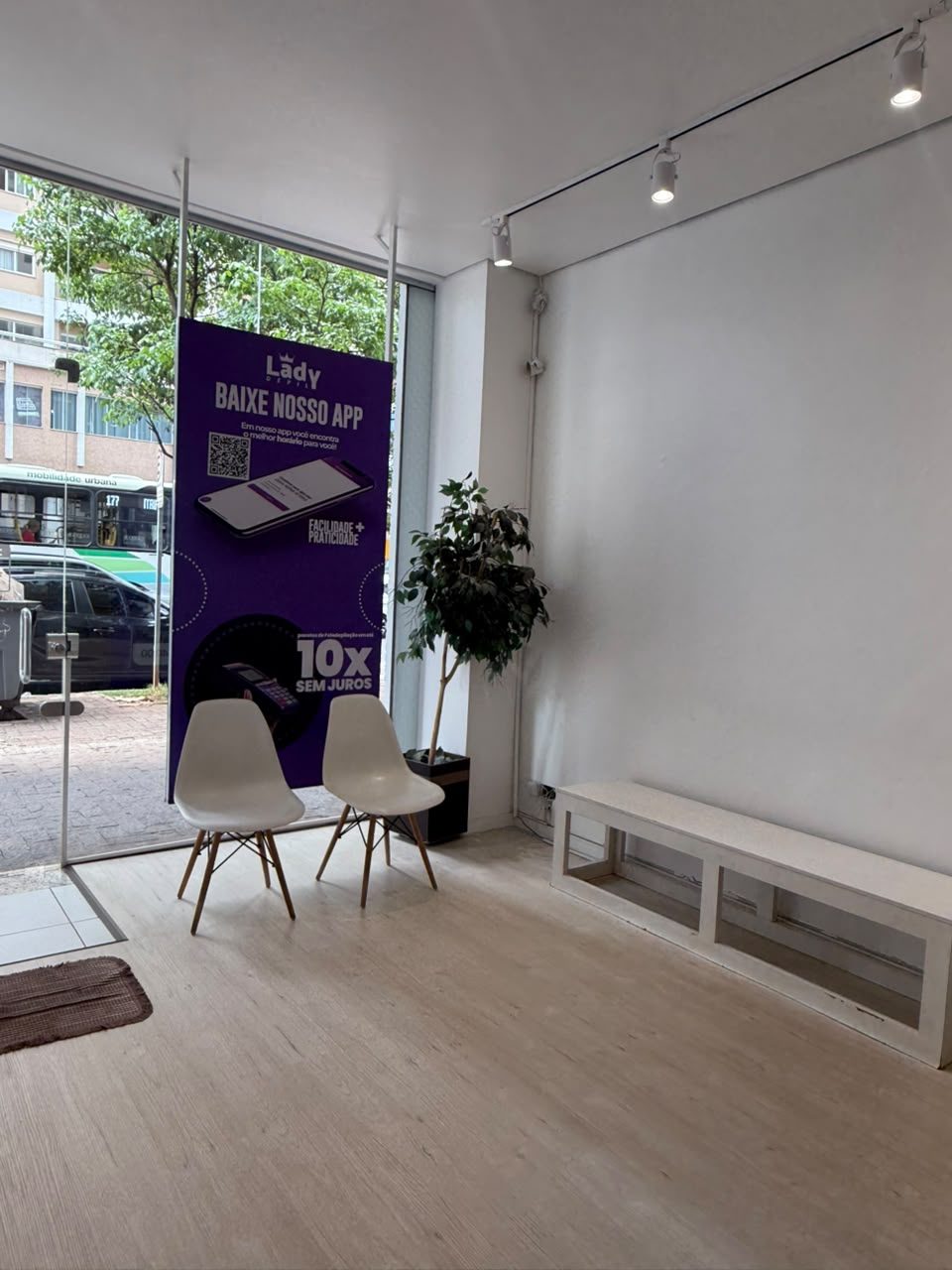 Sala de espera com cadeiras brancas junto à vitrine